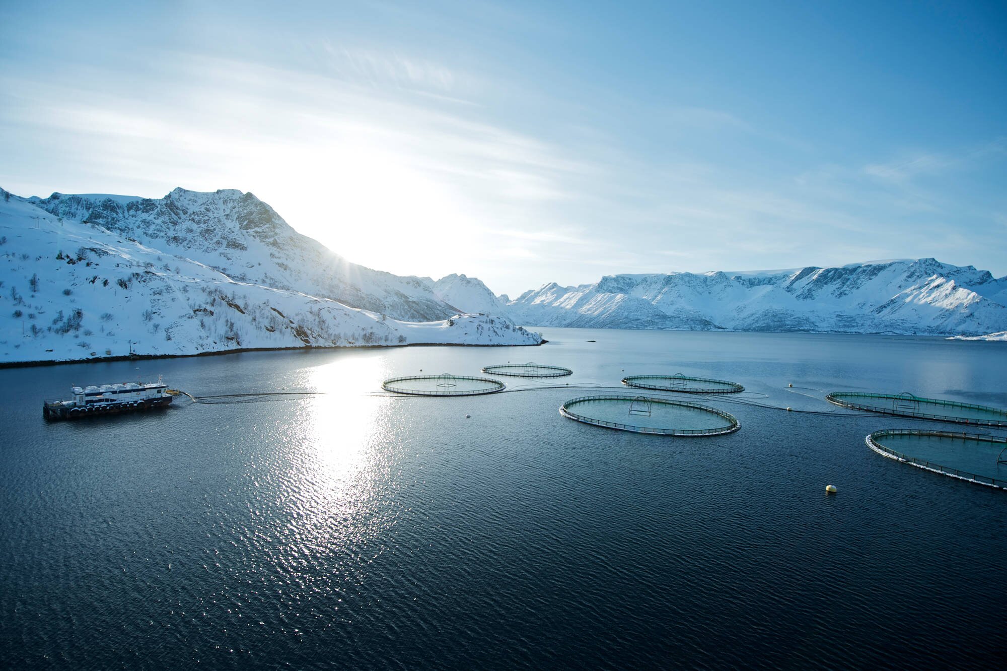 Fish farm in a norwegian fjord with snow covered mountains